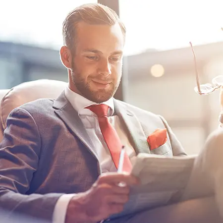 a man in a suit and tie reading a newspaper