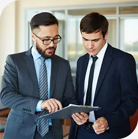 a couple of men in suits looking at a file